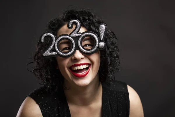 Young beautiful woman is laughing. Brunette with curly hair and red lips. Festive New Year mood. Black background. Close-up. — Stock Photo, Image