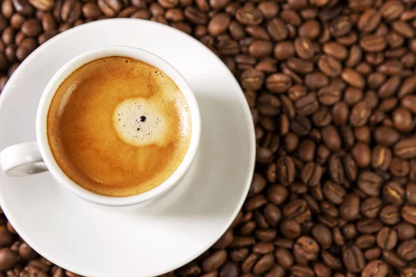 Una pequeña taza de café blanco se encuentra en granos de café. Un placer fragante. Antecedentes Espacio para el texto. Primer plano . —  Fotos de Stock