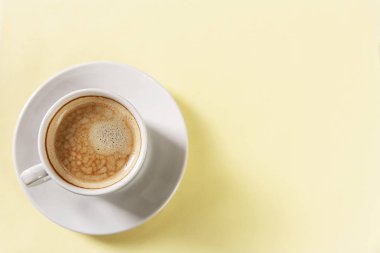 Sarı arka planda beyaz bardakta aromalı kahve.. 
