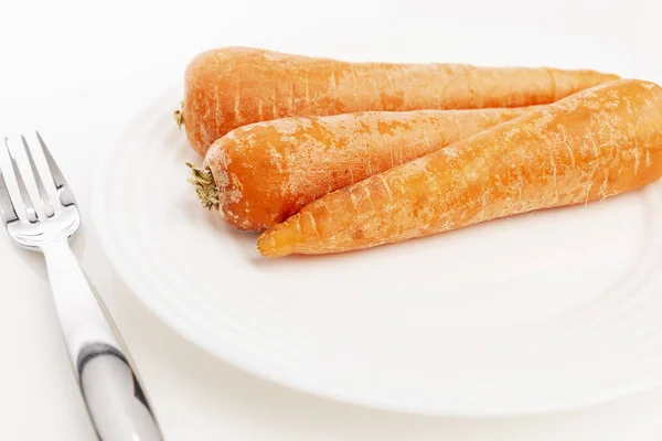 Zanahorias crudas en un plato sobre un fondo blanco. Alimentación saludable Primer plano . — Foto de Stock