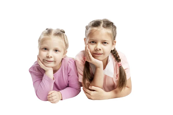 Le bambine con le treccine giacciono lì vicino appoggiando il viso con le mani. isolato su sfondo bianco . — Foto Stock