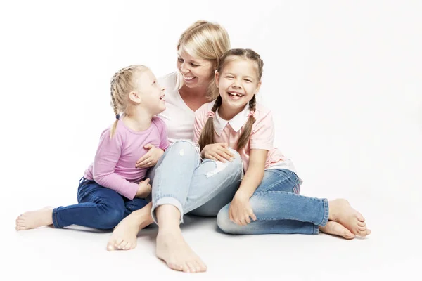 Mutter Blondine mit kleinen Töchtern umarmen und lachen. eine glückliche Familie. weißer Hintergrund. — Stockfoto