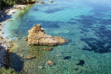 Şeffaf bir turkuaz denizde kalp şeklinde bir taş. Güzel manzara. Metin için boşluk.