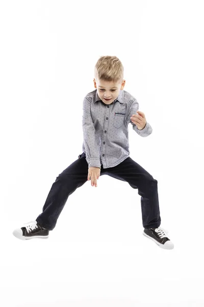 Ein kleiner Junge in blauem Hemd und Jeans springt. weißer Hintergrund. — Stockfoto