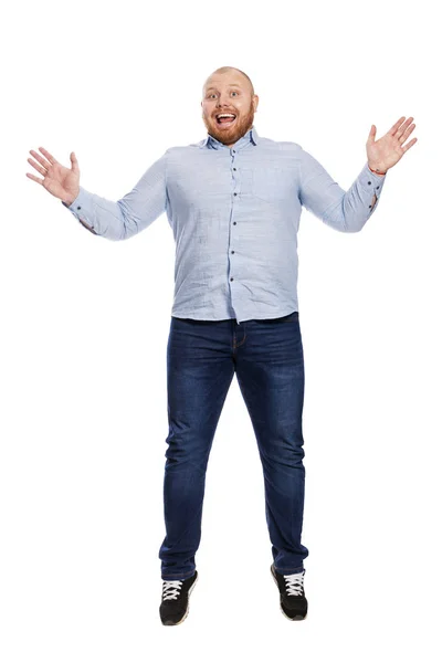 Een glimlachende jonge roodharige man in een blauw shirt en spijkerbroek springt. Op volle hoogte. Geïsoleerd over witte achtergrond. — Stockfoto