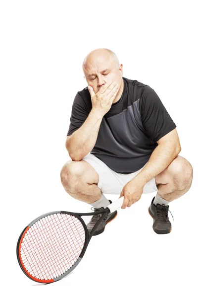 A bald man in an adult in a sports uniform with a tennis racket sits tired. Full height. Isolated over white background. — 스톡 사진