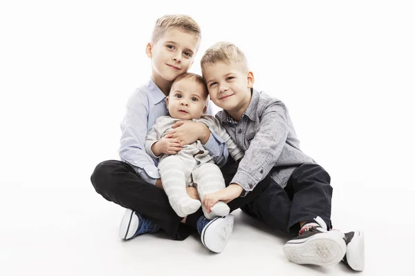 Twee broers hebben een pasgeborene en glimlachen. Liefde en tederheid in de familie. Witte achtergrond. — Stockfoto