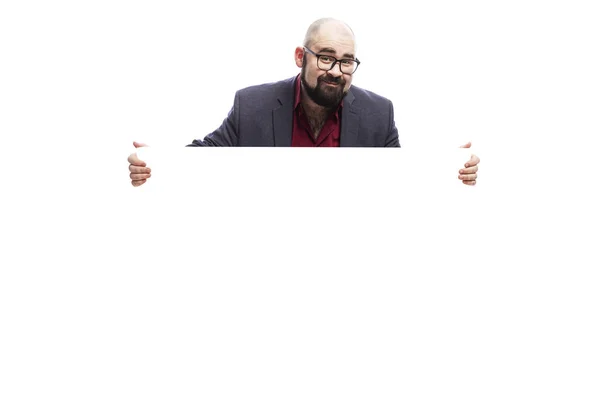 En skallig man med skägg och glasögon håller en tom affisch i sina händer. Isolerad över vit bakgrund. Plats för texten. — Stockfoto