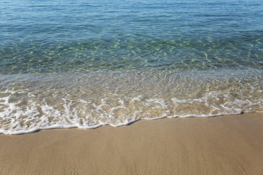 Turkuaz deniz yüzeyi kumlu sahilde. Yakın plan. Geçmişi. Metin için boşluk.