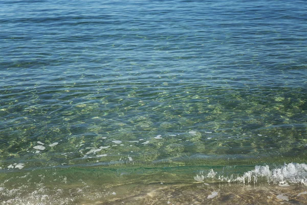 Τυρκουάζ επιφάνεια της θάλασσας στην αμμώδη ακτή. Κοντινό πλάνο. Ιστορικό. Χώρος για κείμενο. — Φωτογραφία Αρχείου