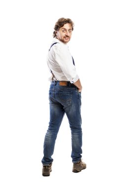 Beyaz gömlekli ve kot pantolonlu gülümseyen bir adam kameraya döndü. Arkadan bak. Tam yükseklik. Beyaz bir arkaplanda izole edilmiş. 