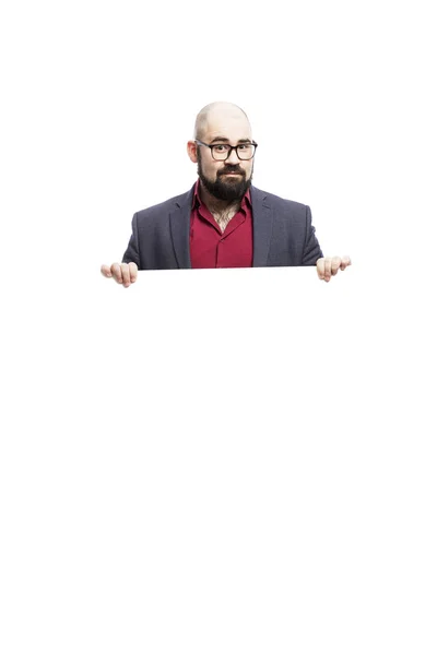 A bald man in glasses with a beard holds an empty banner. Dressed in a formal suit. Isolated on a white background. — Stock Photo, Image