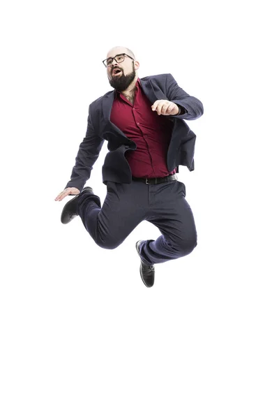 Un hombre calvo con gafas y barba está saltando. Vestido con un traje formal. Aislado sobre fondo blanco . — Foto de Stock