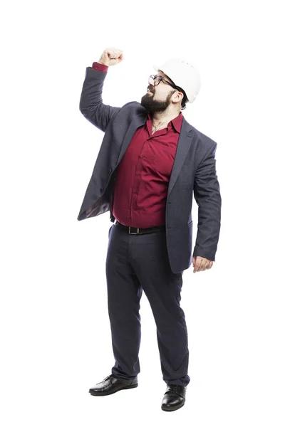 Un hombre con gafas con barba en un casco de construcción blanco muestra el pulgar hacia arriba. Vestido con un traje formal. Aislado sobre un fondo blanco . — Foto de Stock