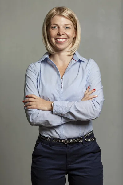Νεαρή χαμογελαστή γυναίκα με μπλε πουκάμισο και παντελόνι. Επιχειρηματική επιτυχία. Γκρι φόντο. — Φωτογραφία Αρχείου