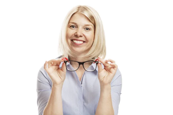 Μια νεαρή χαμογελαστή γυναίκα με κομψά γυαλιά και ένα μπλε πουκάμισο κάθεται στο τραπέζι. Επιχειρηματική επιτυχία. Απομονωμένα σε λευκό φόντο. — Φωτογραφία Αρχείου