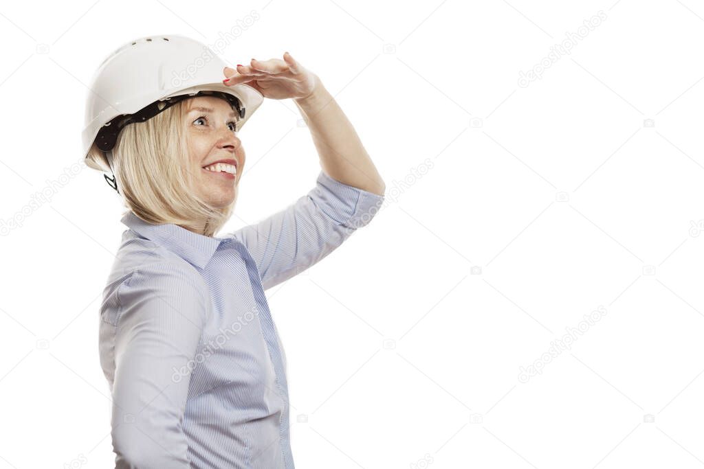 A young woman in a blue shirt and white construction helmet looks into the distance. Isolated over white background. Close-up. Space for text.