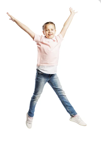 Ein Mädchen im Schulalter in Jeans und rosa Pullover springt. isoliert auf weißem Hintergrund. — Stockfoto