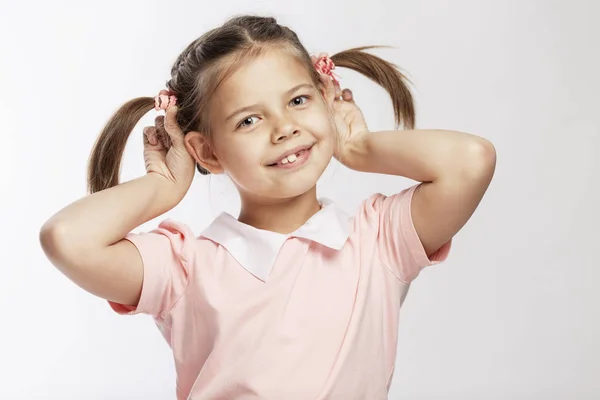 Usmívající se dívka školního věku s culíky na hlavě. Bílé pozadí. — Stock fotografie