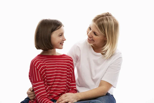 Молодая женщина с дочерью-подростком обнимается и нежно смотрит друг на друга. Белый фон . — стоковое фото