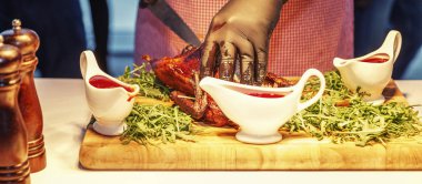 Açık büfedeki siyah eldivenli garsonun elleri kızarmış kabukla iştah açıcı bir kaz kesiyor. Yakın plan.. 