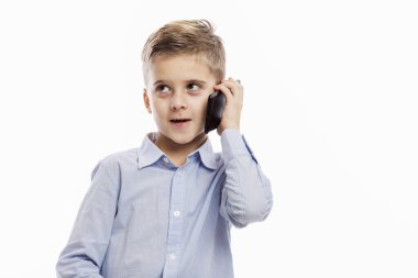 Mavi gömlekli bir okul çocuğu telefonda konuşuyor. Beyaz bir arkaplanda izole edilmiş.
