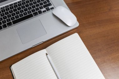 Evdeki ahşap masada dizüstü bilgisayar ve kalemle. Karantinada uzaktan kumanda. Koronavirüs salgını sırasında kendini izole etme rejimi. Yukarıdan görüntüle.