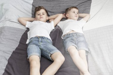 Üzgün çocuklar yatakta uzanıyorlar. Koronavirüs salgını sırasında kendini izole etme. İşaret fişeği.