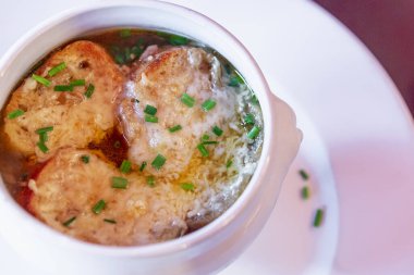 Geleneksel Fransız soğan çorbası bir kafedeki masada beyaz tabakta. Yakın plan..