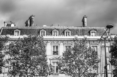 Paris 'in merkezinde kasvetli bir gökyüzüne karşı ağaçların yaprakları arasında güzel, eski bir malikane. Siyah ve beyaz. Metin için boşluk.