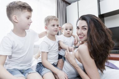 Üç çocuklu gülümseyen anne yatakta sarılıyor. Aile içinde sevgi ve şefkat. Yakın plan..