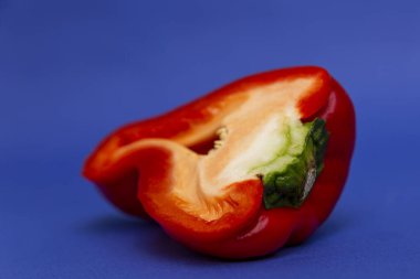 Yarım sulu kırmızı dolma biber. Sağlıklı ve sebzeli beslenme. Parlak mavi arka plan. Yakın plan..