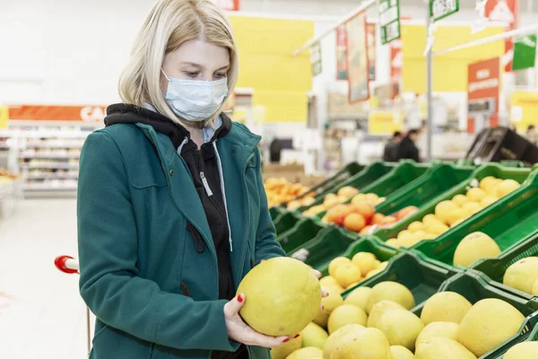 Mulher Loira Uma Máscara Médica Escolhe Frutas Supermercado Precauções Durante — Fotografia de Stock