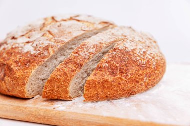 Tahta kesme tahtasında dilimlenmiş taze yuvarlak ekmek. Ev yapımı pişirme. Yakın plan..