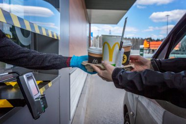 Moskova, Rusya, 26 / 04 / 2020: Arabadaki sürücü McDonald 's vitrininden sipariş alıyor. Koronavirüs salgınının arkaplanına karşı kendini tecrit döneminde popüler bir restoran..
