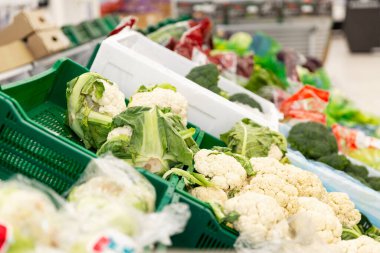 Süpermarketteki bir satış kutusunda bir sürü çeşit yeşil lahana. Yan görüş. Sağlıklı gıdaların geniş çeşitliliği.