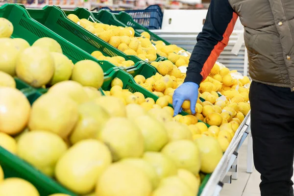 Adult man choosing lemons in the fruit aisle at a supermarket. Bright warm colors, background in focus.