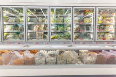 Süpermarketin dondurulmuş ürünler bölümünde bir sıra donmuş sebze. Bulanık.