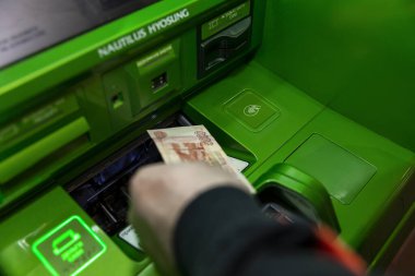 Moskova, Rusya, 04 / 07 / 2020; El, parlak renkli yeşil bir ATM 'den para çekiyor. Arka plan odaklı. Görünür arayüz. 