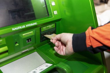 Moskova, Rusya, 04 / 07 / 2020; Banka kartını yeşil bir ATM 'ye sokmak. Yakın çekim, parlak renkler, arayüz.