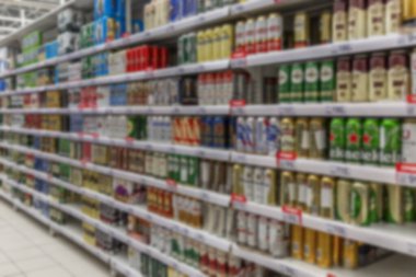 Bir süpermarkette farklı türde alkol satılıyor. Birden fazla renk, fiyat etiketleri. Bulanık.