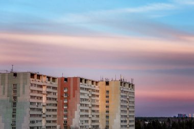 Sovyet döneminin prefabrik evleri mavi gökyüzünde güzel pembe bir günbatımının arka planında. Metin için boşluk.