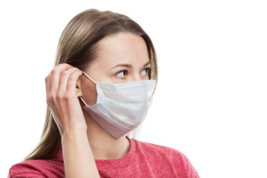 Genç bir kız tıbbi maske takıyor. Koronavirüs salgını sırasında alınan önlemler. Alerjik reaksiyonların önlenmesi. Beyaz bir arka planda izole edilmiş. Yakın plan. Yan görüş. Metin için boşluk.