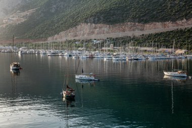 Kas, Türkiye, 05 / 16 / 2019: Dağlardaki küçük bir tatil beldesindeki güzel bir marinadaki yatlar ve küçük ahşap botlar. Turizm ve seyahat. Parlak güneşli bir gün.