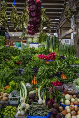 Bitkilerle dolu bir market tezgahı ve çeşitli taze sebzeler. Sağlıklı beslenme ve vejetaryenlik. Ön manzara. Dikey.