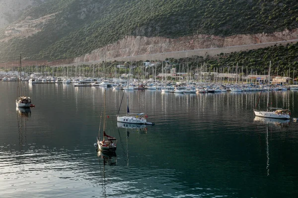 Kas, Türkiye, 05 / 16 / 2019: Dağlardaki küçük bir tatil beldesindeki güzel bir marinadaki yatlar ve küçük ahşap botlar. Turizm ve seyahat. Parlak güneşli bir gün.