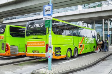 Amsterdam, Hollanda, 10 / 10 / 2019: İstasyonda yeşil uluslararası otobüsler. Bir grup insan salona giriyor..