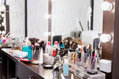 Güzellik salonunda bir sürü makyaj malzemesi olan bir elbise masası..