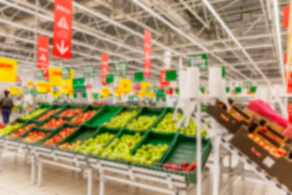 Containers with vegetables and fruits in a supermarket. Large department with a huge selection. Blurred.