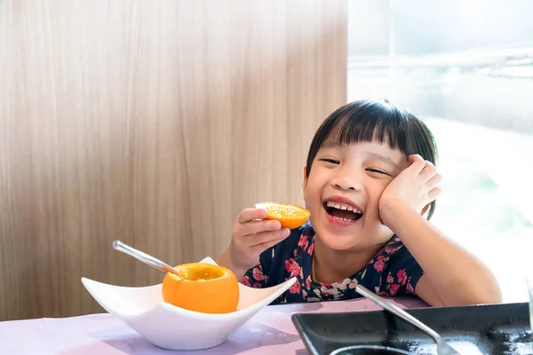 Asian kid girl happy eating fresh orange